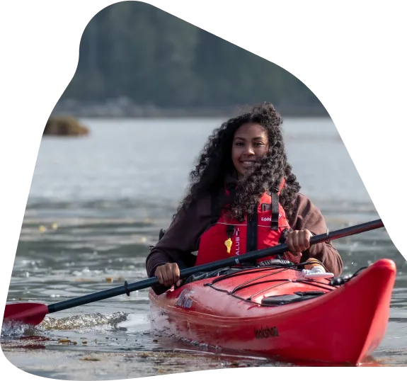 A woman paddling a kayak near shore