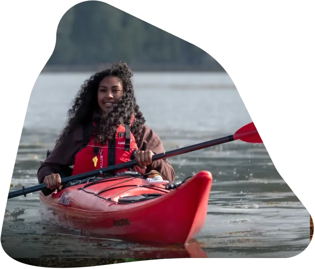 A woman paddling a kayak near shore